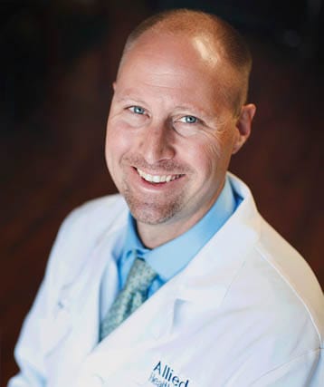 A smiling male doctor in a white coat.